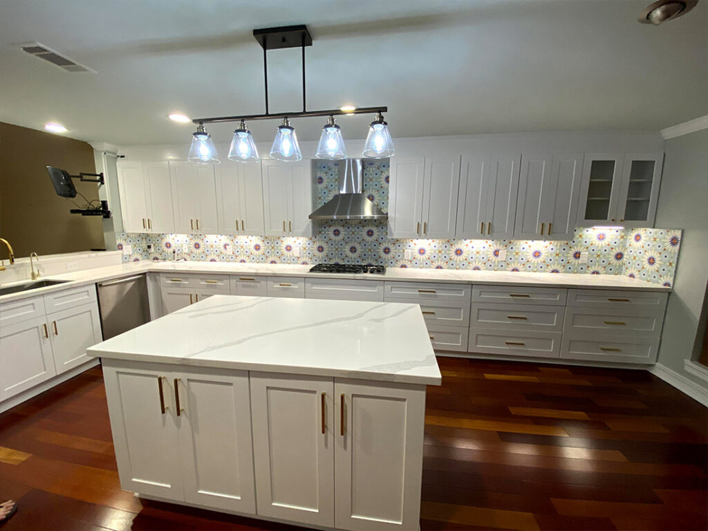 White kitchen shaker cabinets with calacatta wave quartz and 6x6 patterned tile backsplash.