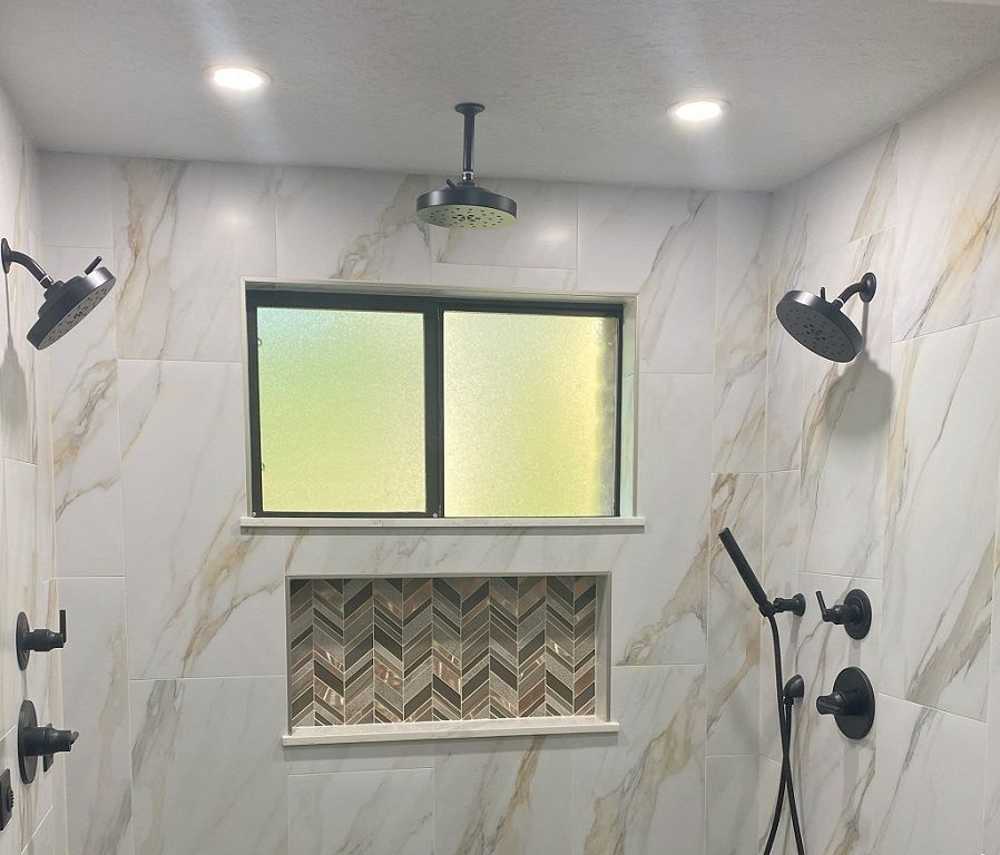 Shower remodel with large porcelain tiles, a rainhead, handheld, 2 showerheads and body sprays.